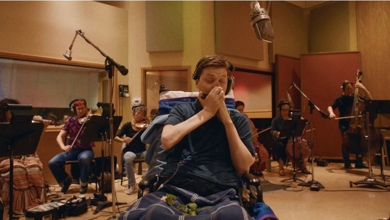 Mac playing the harmonica in front of the studio orchestra during a recording session.